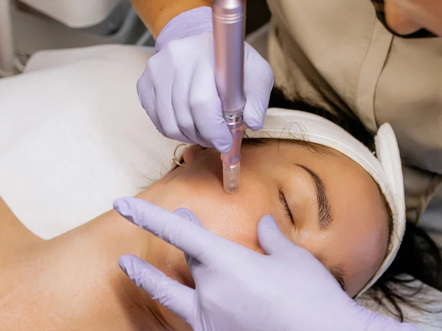 Practitioner in purple gloves performing a facial skin treatment on a client.
